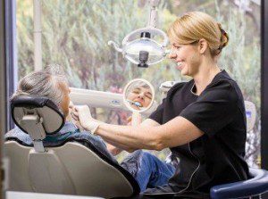 Leean king, dental hygienist, conducting clinical procedure on female patient's front teeth