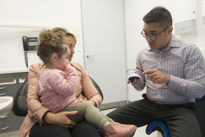 Dr jasper lee, associated dentist showing a young patient how to brush their teeth