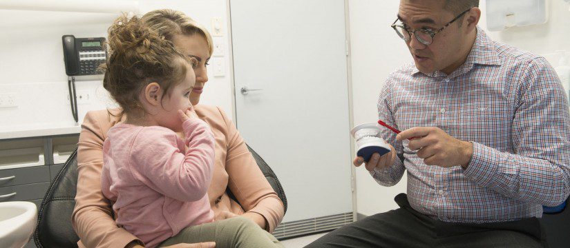 Dr Jasper Lee, associated dentist showing a young patient how to brush their teeth